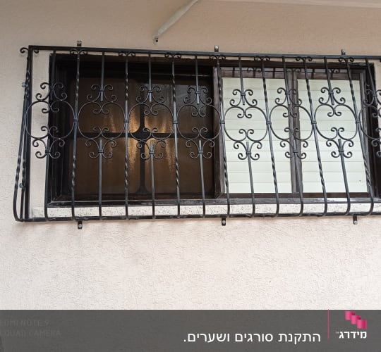 סורגי ברזל מעוצבים על חלון זכוכית
